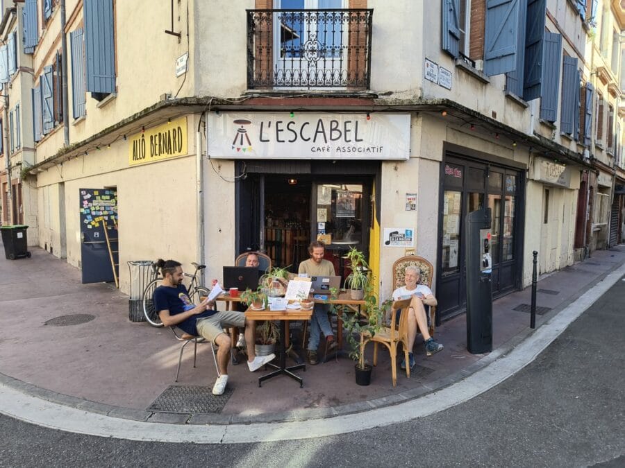 Café associatif de l'Escabel à Toulouse, bureaux sur le trottoir, fauteuils et gens qui travaillent dehors