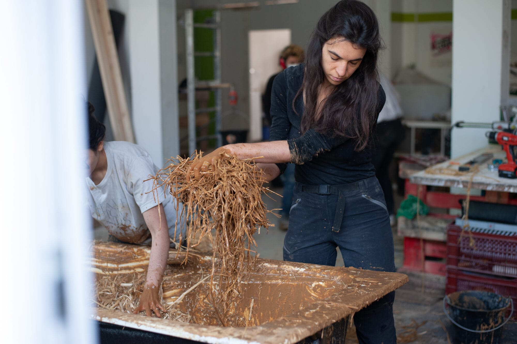 femme avec paille et enduit pour réaliser une isolation thermique écologique à la Grande Coco Paris - crédit Tom Klapisz