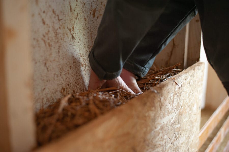 mains mettant de la paille pour réaliser une isolation thermique écologique à la Grande Coco Paris chantier participatif - crédit Tom Klapisz