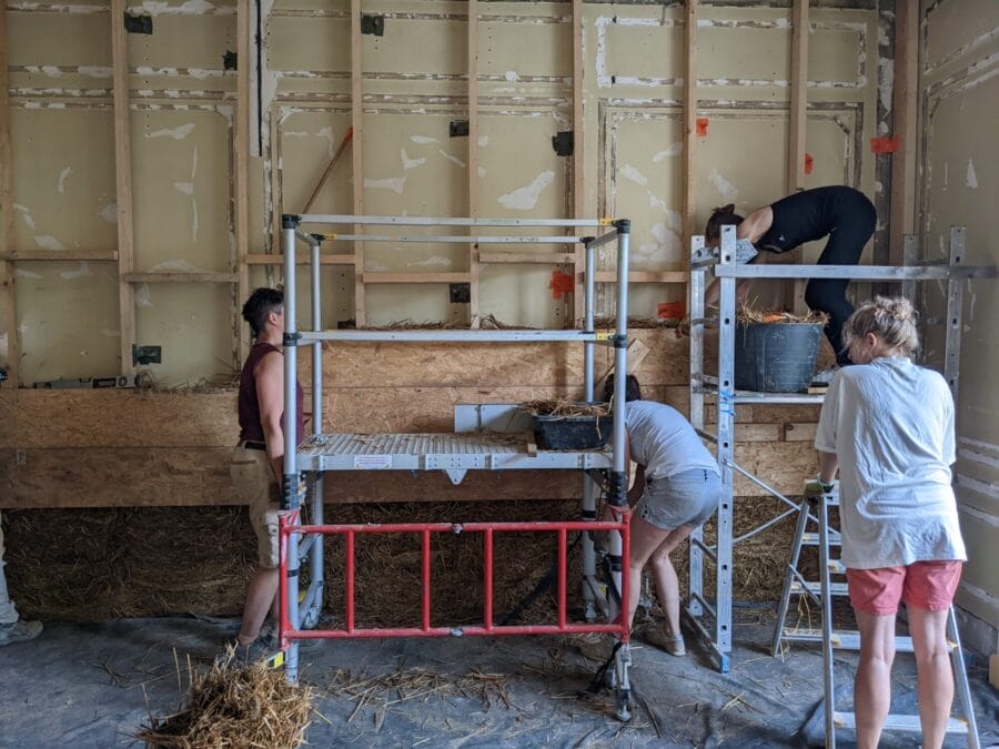 chantier participatif d'isolation en paille à la Grande Coco Paris, échafaudage et personnes travaillant avec de la paille et des matériaux naturels