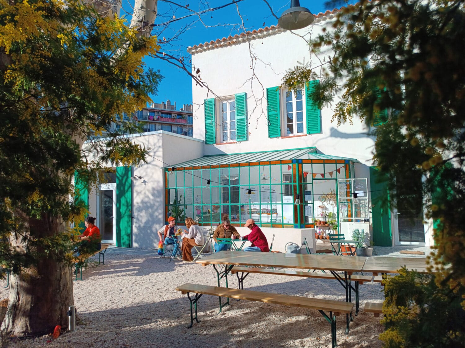 Le Tiers-Lab des Transitions à Marseille, bâtiment rénové, jardin et tables avec gens assis dehors