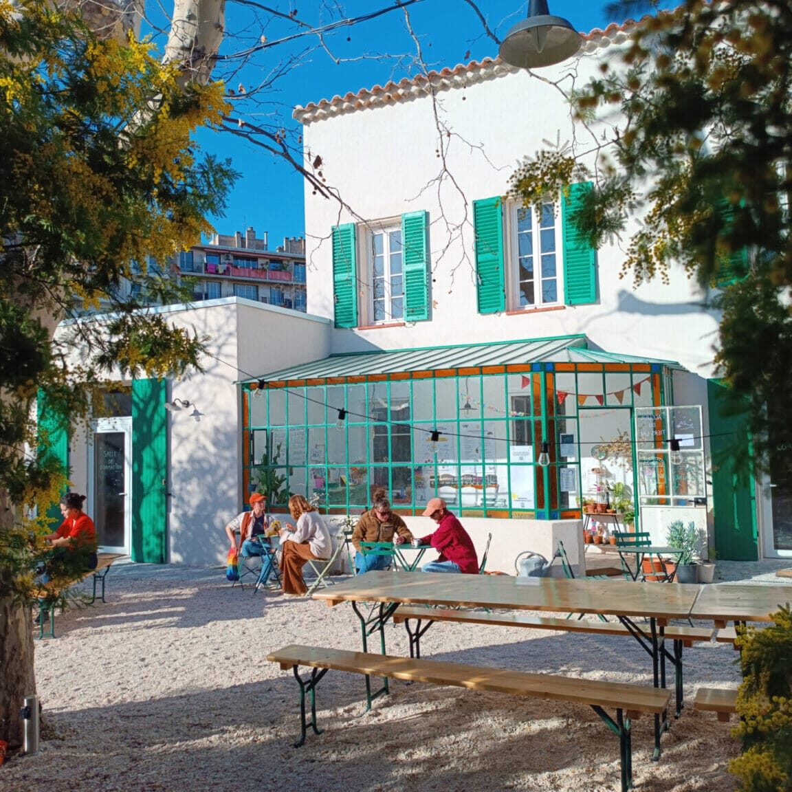 Le Tiers-Lab des Transitions à Marseille, bâtiment rénové, jardin et tables avec gens assis dehors