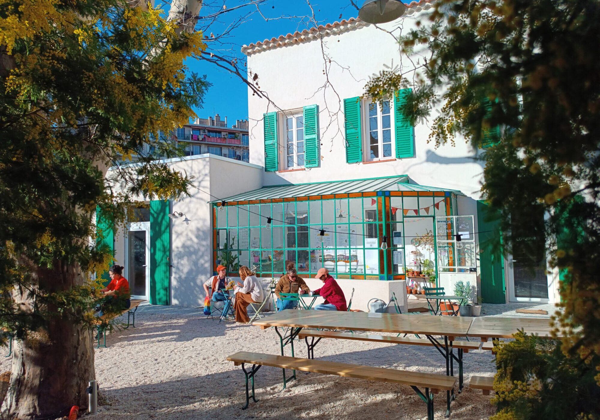 TIERS LAB DES TRANSITIONS_batiment2_credit Tiers Lab des Transitions Le Tiers-Lab des Transitions à Marseille, bâtiment rénové, jardin et tables avec gens assis dehors
